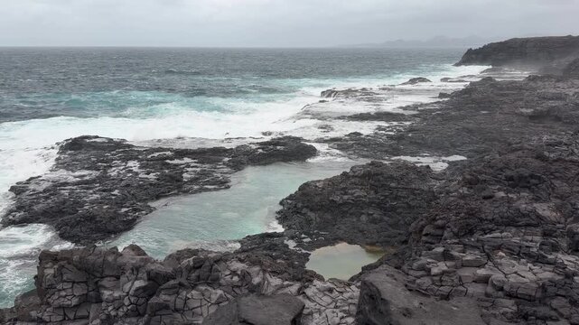 Olas rompiendo en charcos naturales volc&aacute;nicos en la costa de Lanzarote