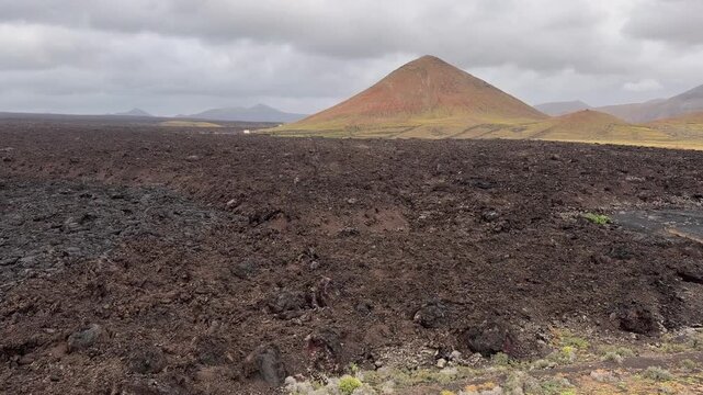 Paisaje volc&aacute;nico de Timanfaya con campo de lava y cono volc&aacute;nico en Lanzarote