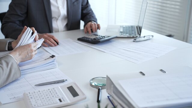 Accountants processing financial documents and working on tax audit calculations in an office setting. Audit and taxes in business
