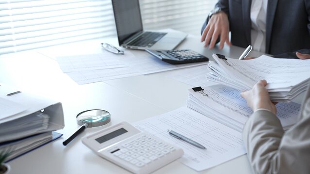 Accountants processing financial documents and working on tax audit calculations in an office setting. Audit and taxes in business