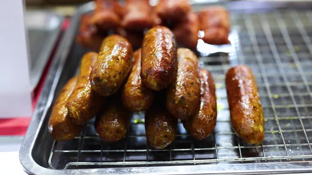 Sai ua grilled northern thai spicy sausage on metal tray at street food market close up motion shot.