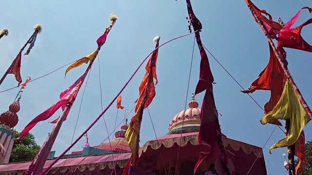 Yerad's Yedoba Temple shines during Chaitra Yatra. Vibrant Sasan Kathis & flags dance amidst gulal at the Chhabina. The ornate temple kalash stands tall against the sky during this lively celebration.