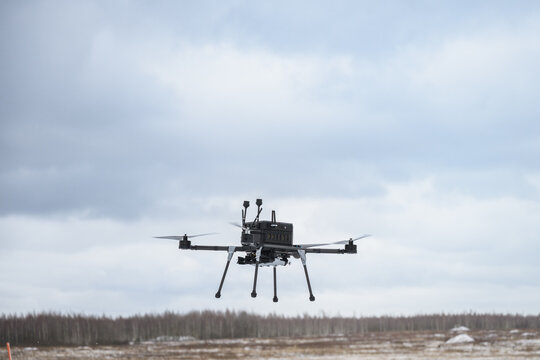 Military bomber drone equipped with payload release system flying over field. Modern aerial warfare technology used for strike missions and tactical operations.