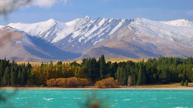 Stunning scenic motion of lake tekapo with turquoise water and snowy mountains in the background under clear sky.