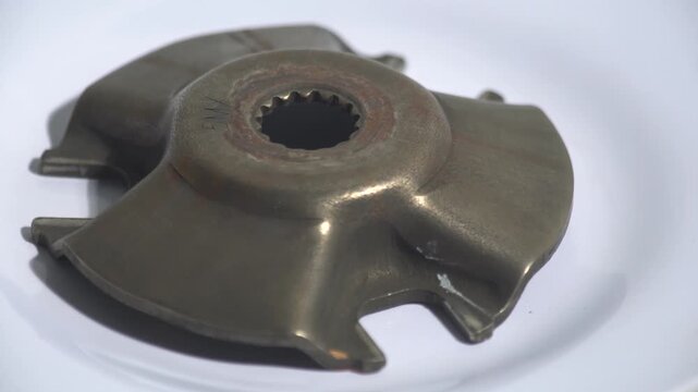 Detailed 4K shot of a motorcycle CVT variator ramp plate. The metal part features a splined center and worn surface, ideal for automotive tutorials, mechanical engineering presentations, and vehicle m