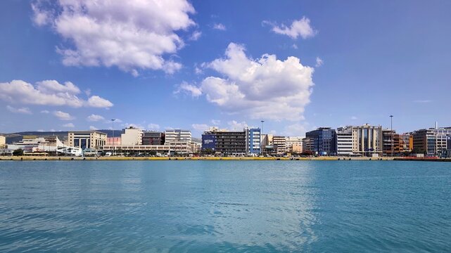 A wide-angle view of Akti Kondyli Avenue along the waterfront at the Port of Piraeus, Greece, lined with commercial buildings and offices. 