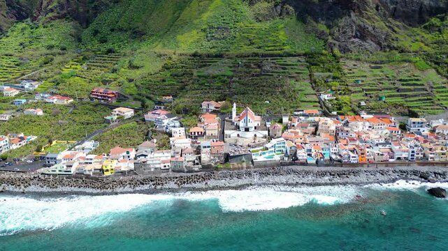 Aerial view of Paul do Mar, Madeira, where a charming village nestles between lush, terraced mountains and the Atlantic Ocean.
