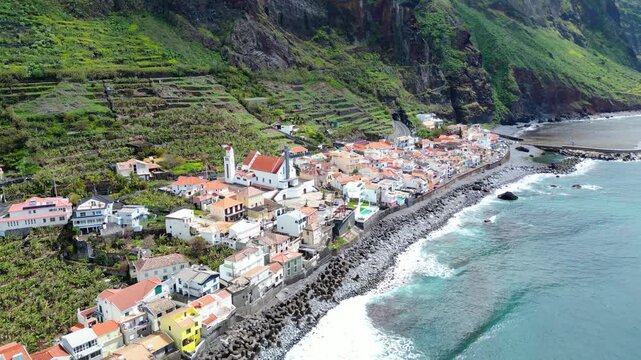Aerial view of Paul do Mar, Madeira, where a charming village nestles between lush, terraced mountains and the Atlantic Ocean.