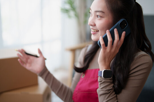 Young asian woman entrepreneur talking on mobile phone, managing, selling online products for small business, smiling while having customer conversations