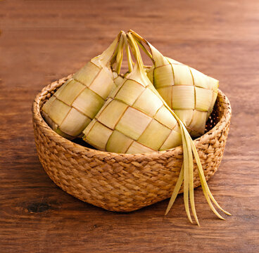 Traditional Thai Sticky Rice Parcels in Woven Coconut Leaves on Rattan Basket, Rustic Wooden Table