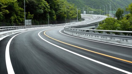 Naklejka premium Winding Road Through Lush Green Landscape with Guardrails and Smooth Pavement Under Clear Blue Sky