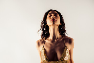 Confident woman in gold sequin dress portrait with eyes closed, elegant fashion pose conveying...