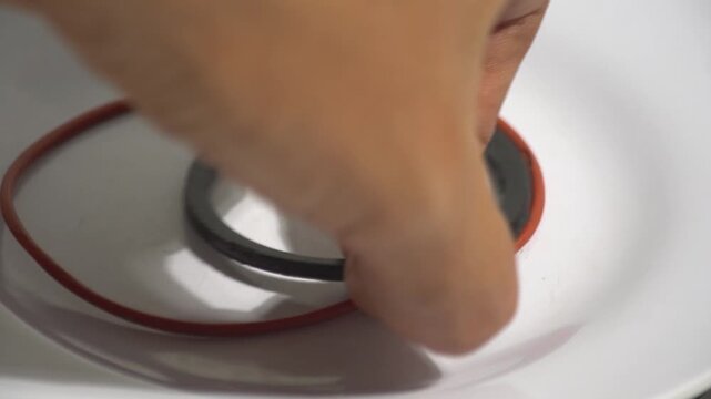 Close up of hand picking up rubber o-ring seal and gasket from a white background. Perfect for automotive repair, engine maintenance, mechanical spare parts, industrial seal equipment, and technical r