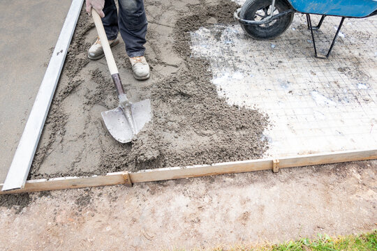 Worker leveling fresh concrete for slab foundation