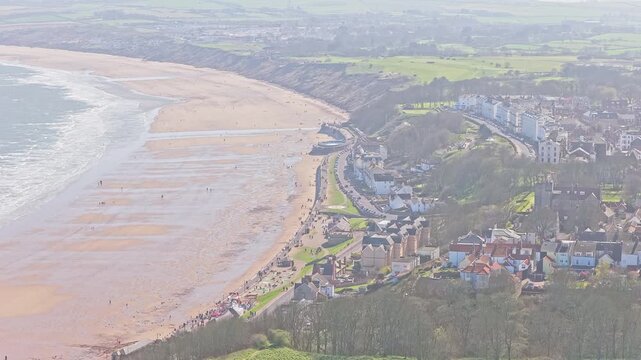 Filey Bay in Filey North Yorkshire England with Ravine Road, Filey Promenade and The Crescent cliff top terraces overlooking wide sandy beach and North Sea within embayed coastal system, drone view