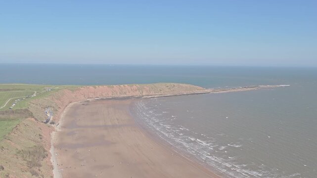 Carr Naze cliffs transitioning into Filey Brigg in Filey North Yorkshire England with eroding coastal headland and Jurassic rock platform forming northern boundary of Filey Bay on North Sea, aerial