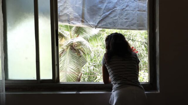 An Indian woman standing in her balcony with palm tree view