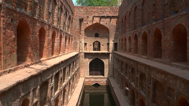A static wide shot showing the symmetrical rows of arched niches and the central water reservoir of the historic Agrasen ki Baoli stepwell, a 14th-century monument in New Delhi.