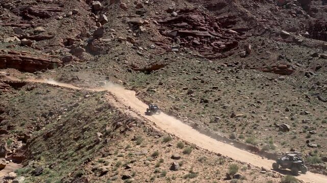 4x4 UTVs traveling along Chicken Corners trail near Moab in Grand County Utah USA within Colorado Plateau canyon landscape with Entrada Sandstone formations and desert terrain, tracking shot pan