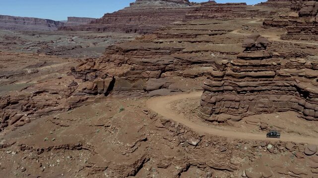 UTV navigating a hairpin bend into layered sandstone along Chicken Corners trail near Moab in Grand County Utah USA showing off road navigation through rugged desert terrain and exposed canyon edges