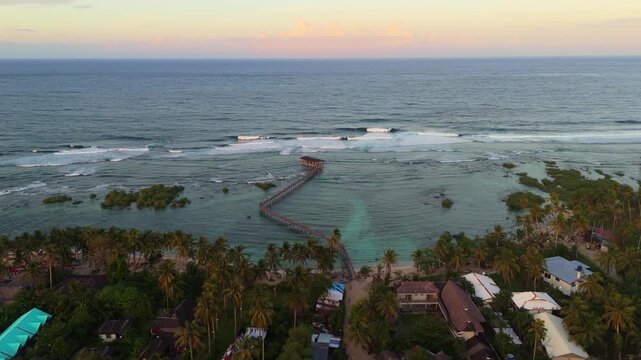 Aerial of General Luna coastline at sunset, Siargao Island . Drone shot of the lush palm tree forest and Cloud 9 boardwalk famous surfing spot in Philippines