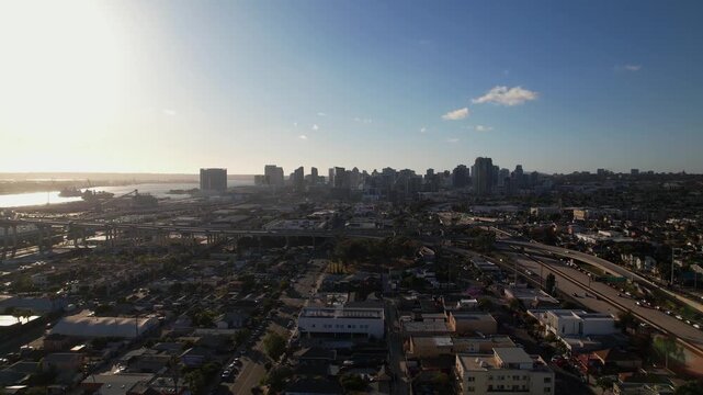 Drone flying north toward downtown San Diego at 6PM capturing a wide view of the skyline and surrounding city.