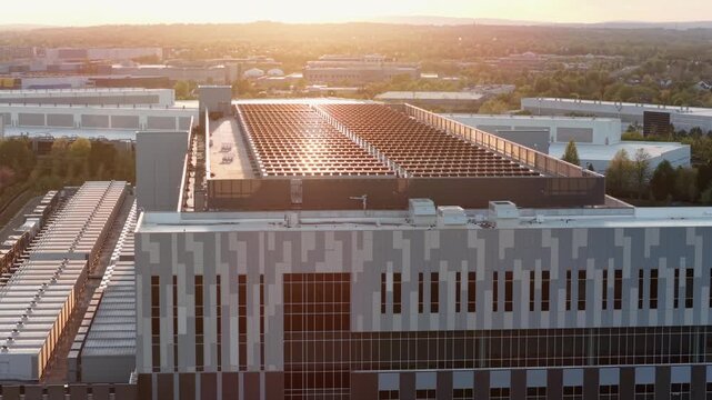 Aerial sunset rise flyover of modern data center in Ashburn, Virginia showing large scale server infrastructure and cooling systems representing AI cloud computing and future digital technology
