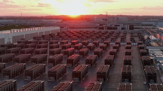 Aerial drone view of expansive data center campus in Ashburn, Virginia at sunset with row of cooling units, showing large-scale cloud computing, AI infrastructure and modern digital technology systems