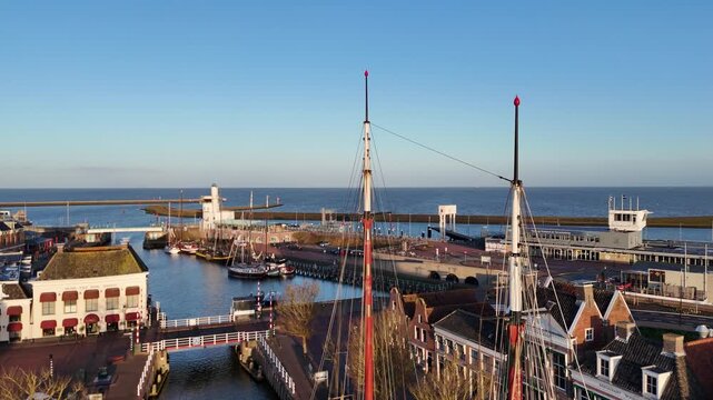 Steady aerial at mast height with bridge traffic, rigging lines and harbor background.
