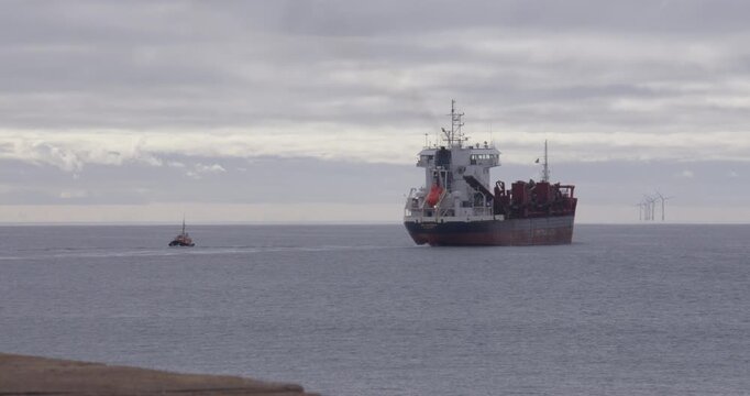 Wide shot of a port harbour boat pilot leaving a large commercial ship at Shoreham harbour