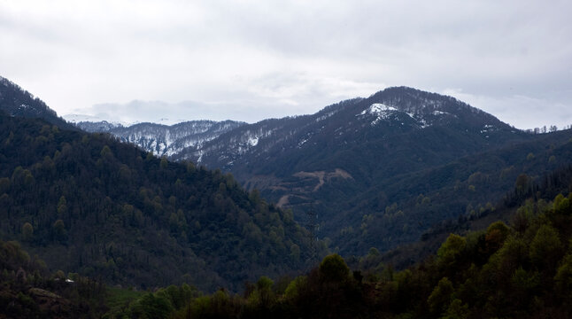 Panoramic view of green mountain slopes and snow-capped peaks