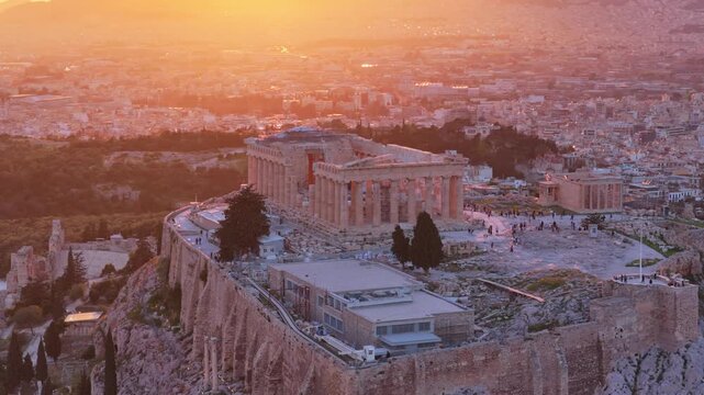 Majestic aerial view of the ancient parthenon temple on the acropolis hill, beautifully illuminated by the warm, golden light of the setting sun over the sprawling cityscape of athens, greece