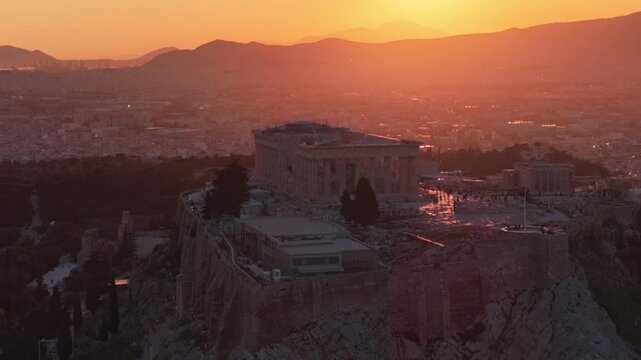 Breathtaking aerial view of the acropolis of athens and the parthenon bathed in the warm, golden light of a dramatic sunset, with the cityscape and distant mountains creating a scenic panorama
