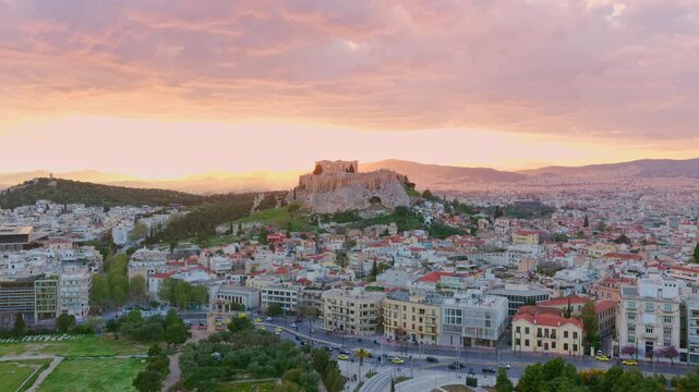 Golden hour light illuminating the cityscape of athens and the iconic acropolis, with the parthenon perched atop the rocky citadel, under a beautifully colored sky during a vibrant sunset