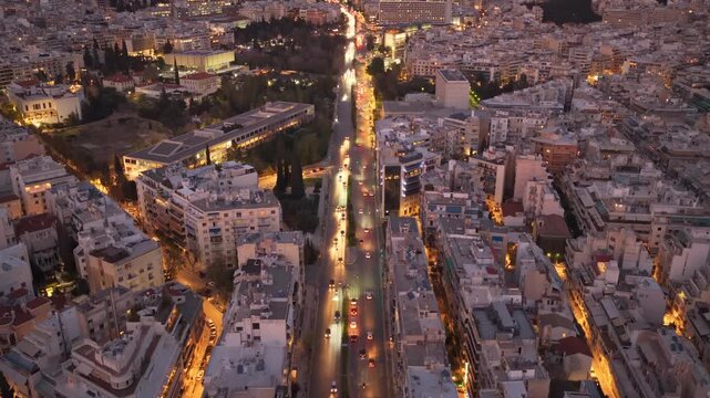 Beautiful aerial perspective of athens, greece, during the evening blue hour, showcasing the illuminated cityscape and the vibrant flow of traffic along a central avenue surrounded by buildings
