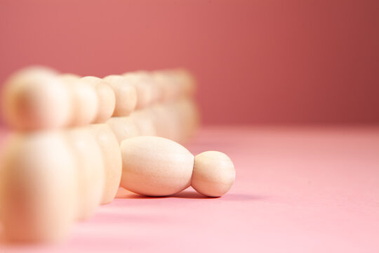 Wooden figures on a pink background. The concept of leadership.