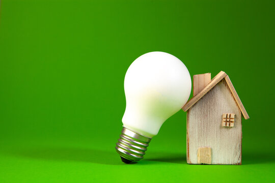 Idea concept with light bulb and house model on green background.