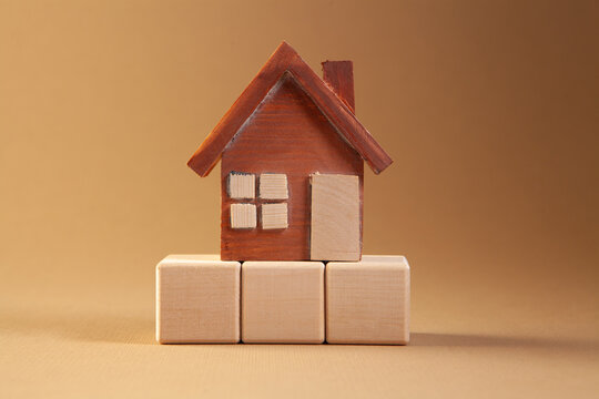 Wooden toy house on a brown background. The concept of buying and selling real estate.