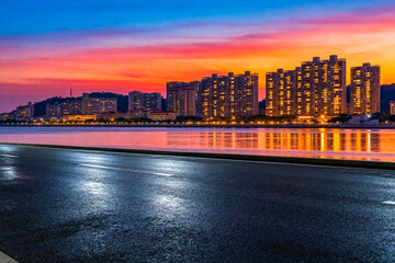 Naklejka premium Sunset over city buildings with illuminated windows