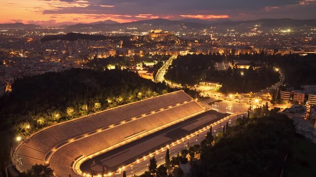 Illuminated city of athens at night with the panathenaic stadium in the foreground and the acropolis on the hill in the background, showing a beautiful colorful sky during the blue hour sunset