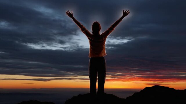 Reaching for the Horizon: Silhouette of person with outstretched arms stands atop a mountain ridge, embracing the vastness of the sky during a breathtaking sunset.