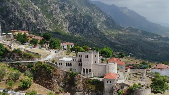Stunning aerial view of the historic Kruje Castle, a medieval fortress perched on a rocky hill with majestic mountains in the background