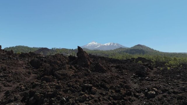 Aerial view from a drone flying over lava fields in the highlands of western Tenerife with Mount Teide in the background. Mirador de los Poleos 