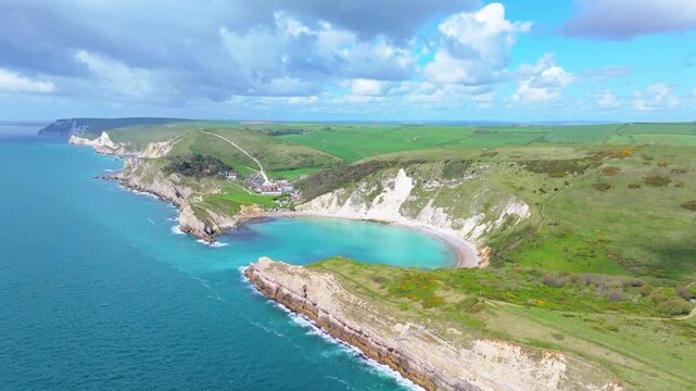Tracking wide aerial shot of Lulworth Cove and Jurassic coastline on a sunny day