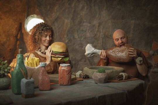 Primitive stone age couple having a delicious lunch in their cave