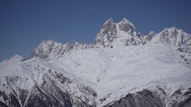 Zooming camera moving across Ushba mountain peak in Caucasus, Georgia. Snow-covered alpine summit with slight handheld motion, immersive high mountain landscape