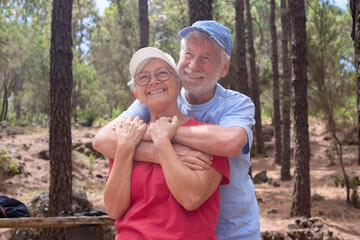 Fototapeta premium Happy senior couple hugging enjoying mountain hike in the woods appreciating nature and freedom, retired seniors man and woman and healthy lifestyle concept
