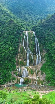 Majestic tropical waterfall cascading down a lush green cliff in a dense forest, Guizhou, China
