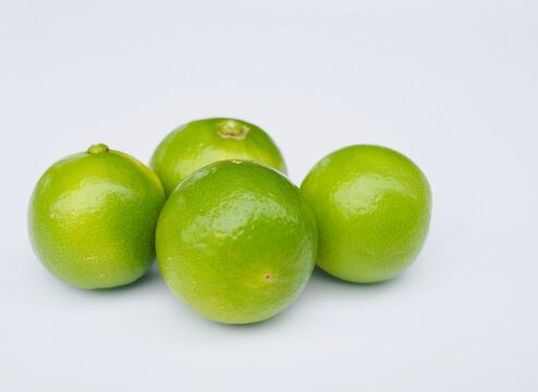 Several fresh green lemons are placed on a white background.