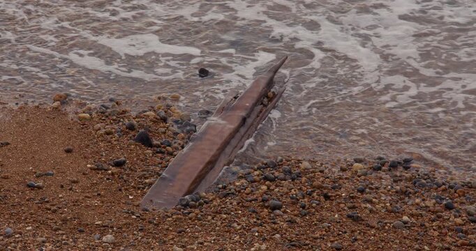 Wide shot of waves lapping over old peach of wood next to Shoreham harbour